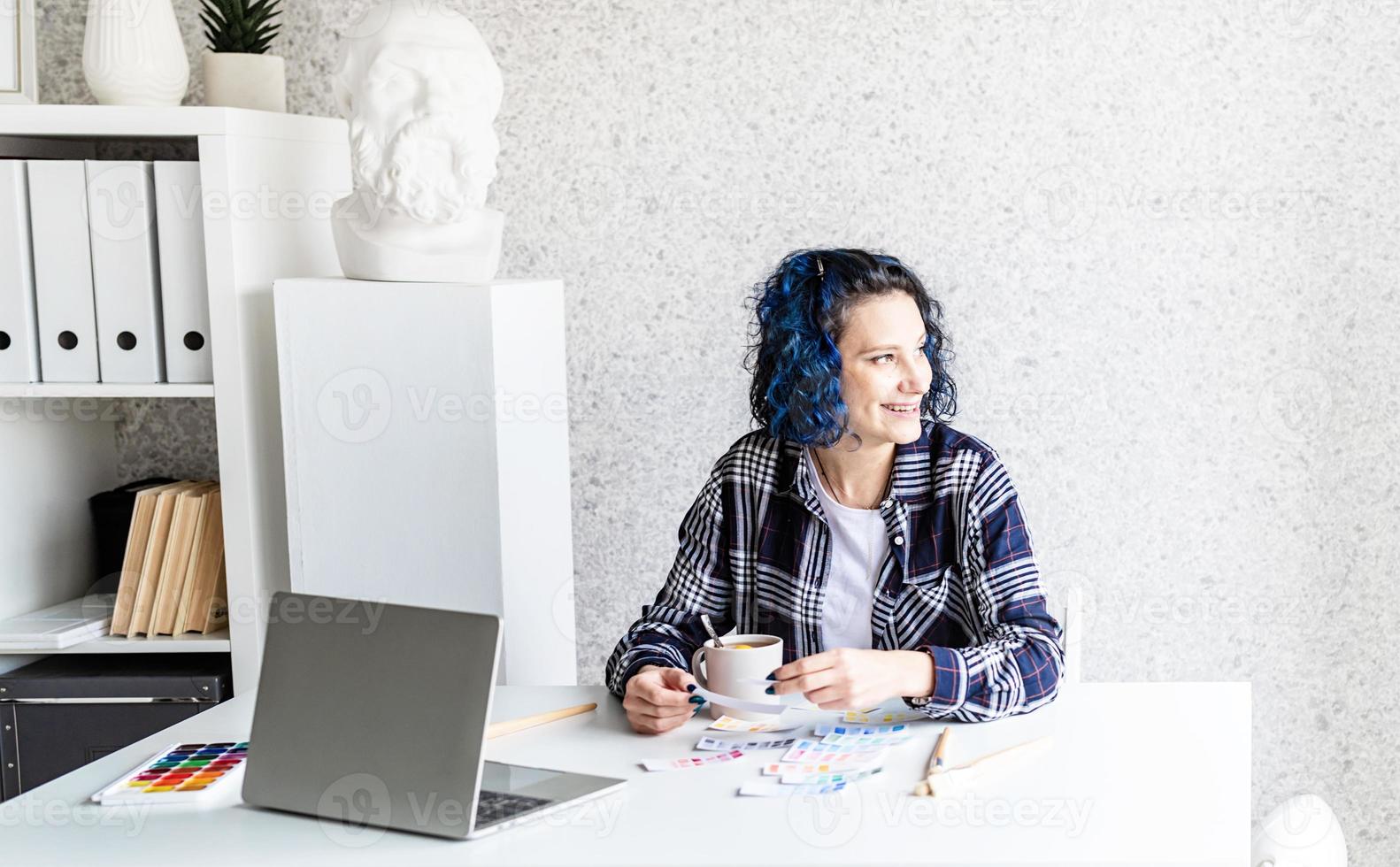 Designer working with colour palettes and laptop in her studio photo