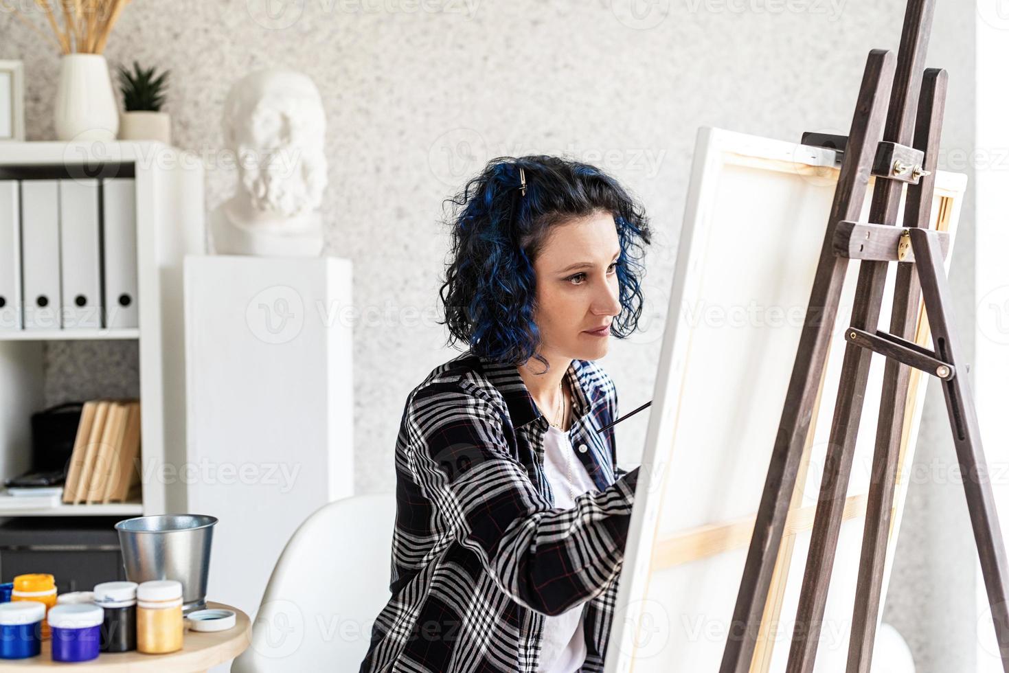 Mujer creativa con pintura de cabello teñido de azul en su estudio foto