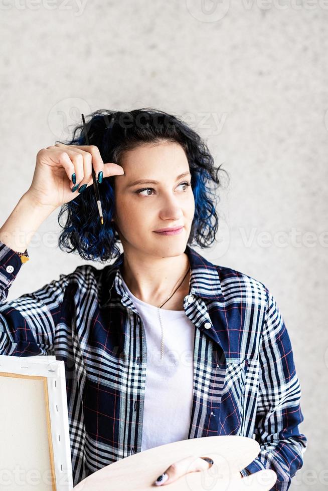 Mujer creativa con pintura de cabello teñido de azul en su estudio foto