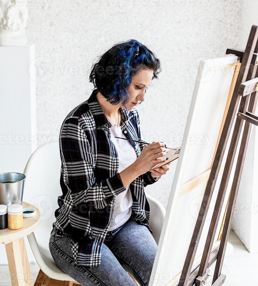 Mujer creativa con pintura de cabello teñido de azul en su estudio foto