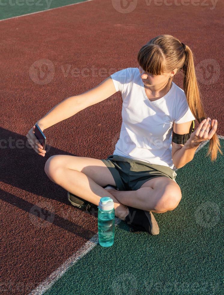 Teen girl making selfie at the stadium after workout photo