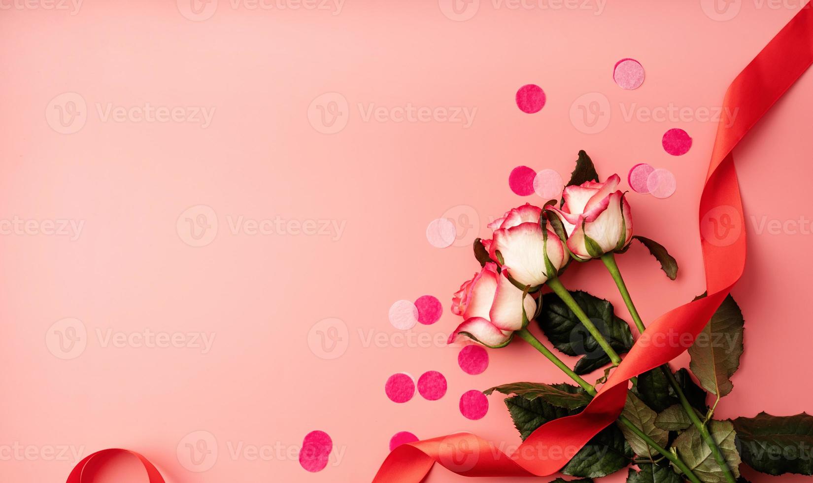 Pink roses with confetti on solid pink background photo