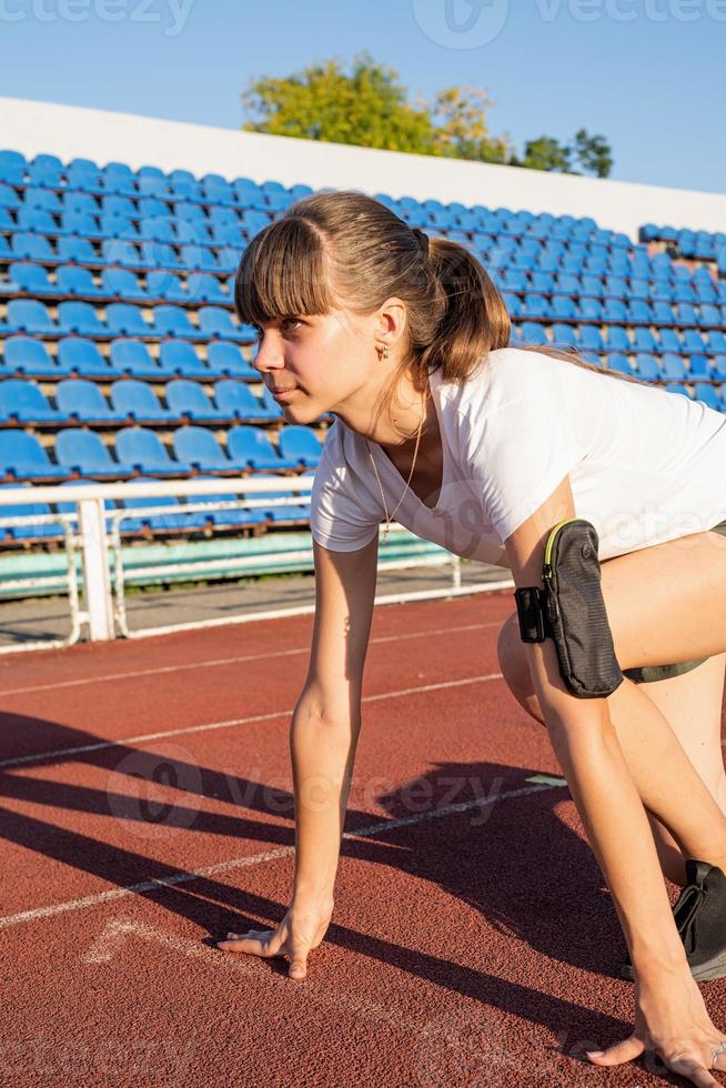 Mujer joven lista para correr en la pista del estadio foto