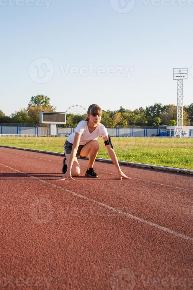 Young woman ready to race at stadium track photo