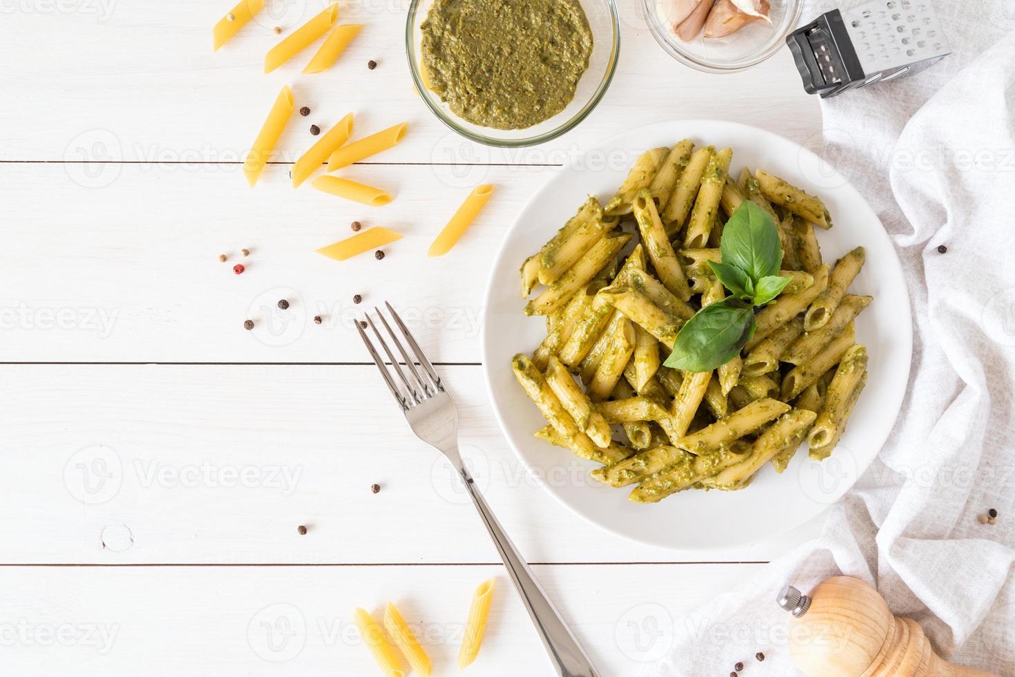 Vegan penne pasta in a basil pesto sauce top view flat lay photo