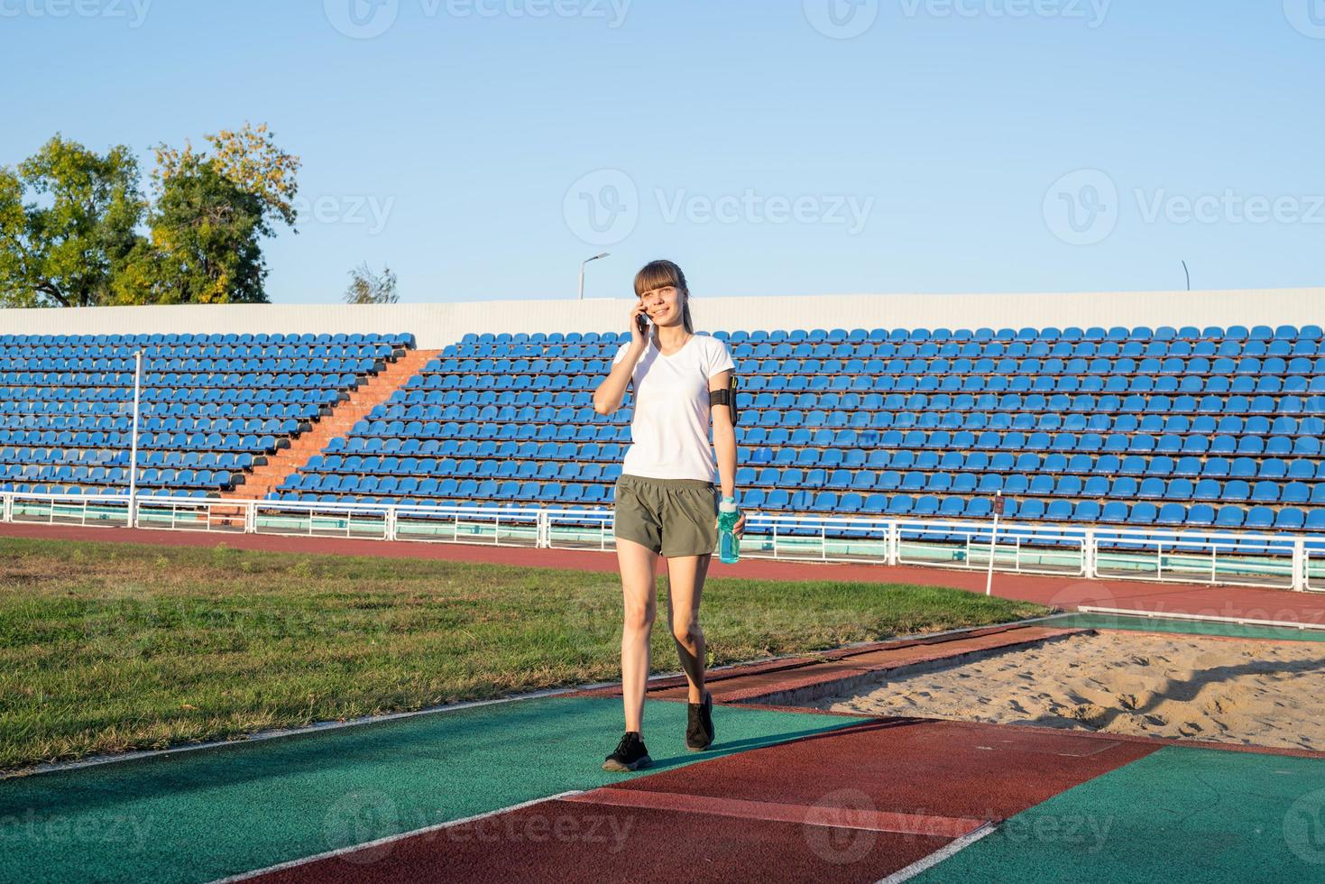 Young sports woman talking on the phone at the stadium photo