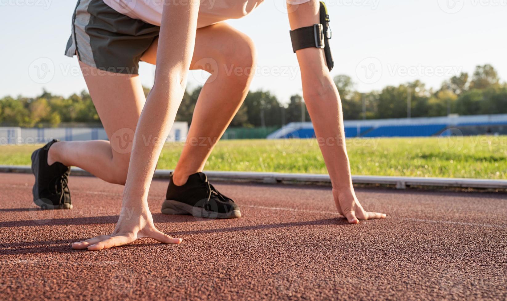 Mujer joven lista para correr en la pista del estadio foto