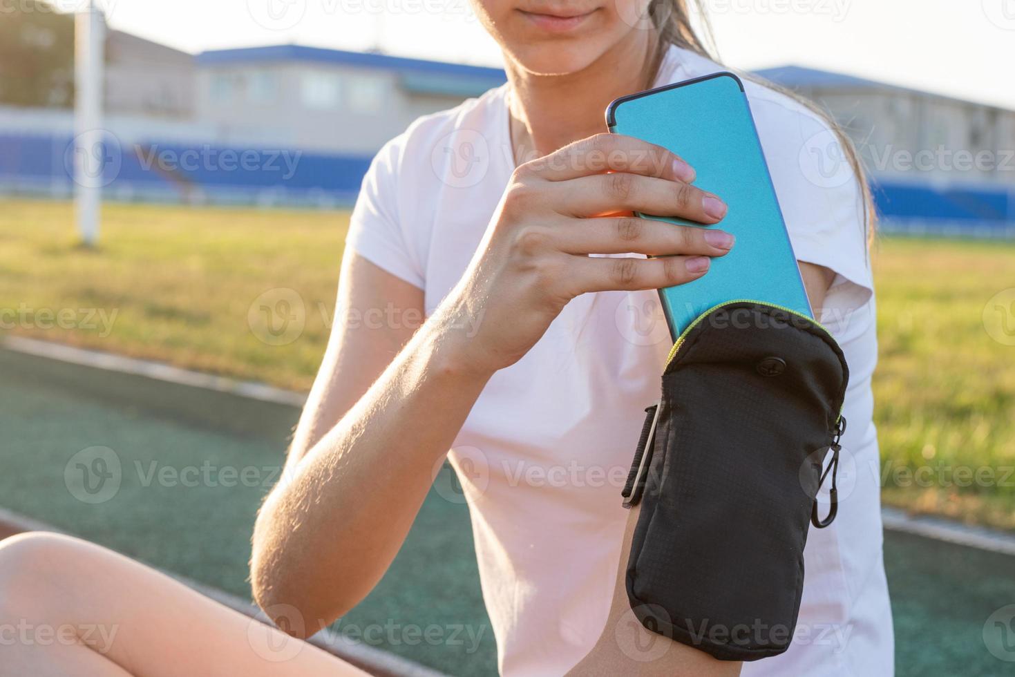 Adolescente en el estadio poniendo su teléfono móvil en el bolsillo. foto