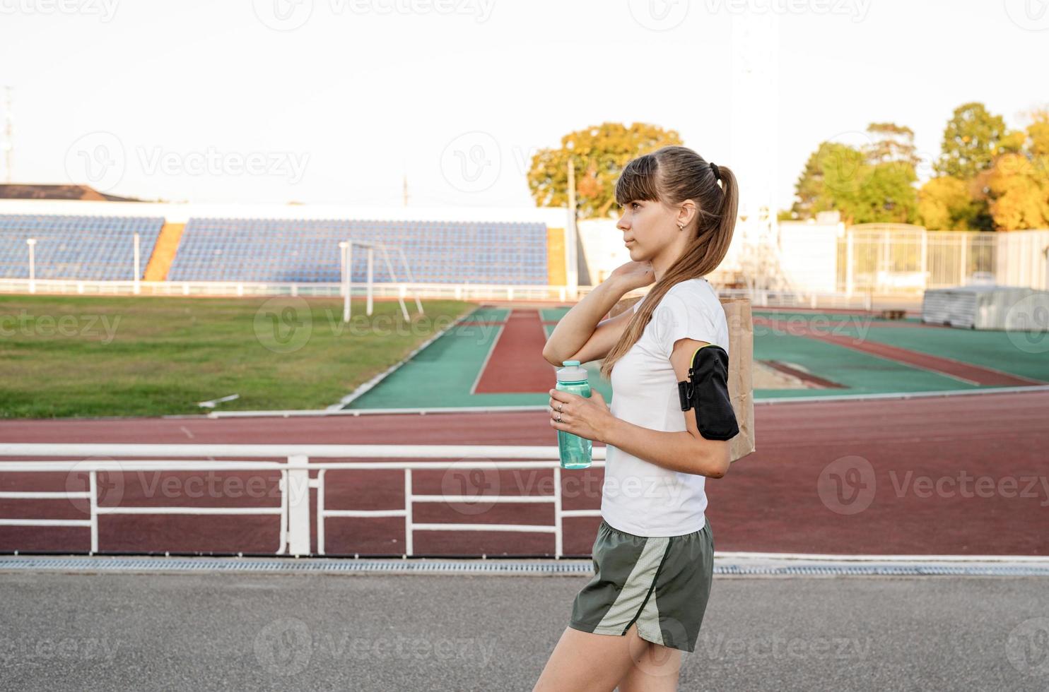 Chica adolescente caminando en el estadio con la bolsa de papel después del entrenamiento foto