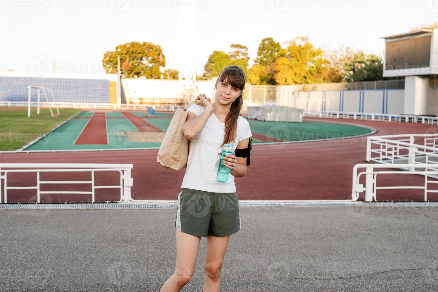 Chica adolescente caminando en el estadio con la bolsa de papel después del entrenamiento foto