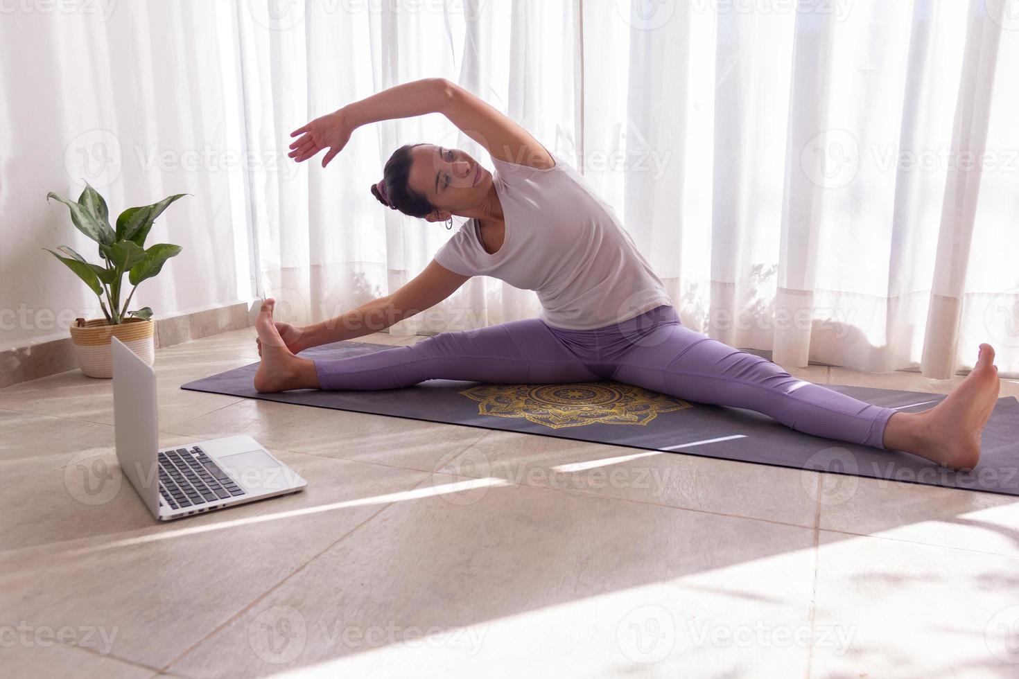 mujer joven, estirar, en, ella, estera de yoga foto