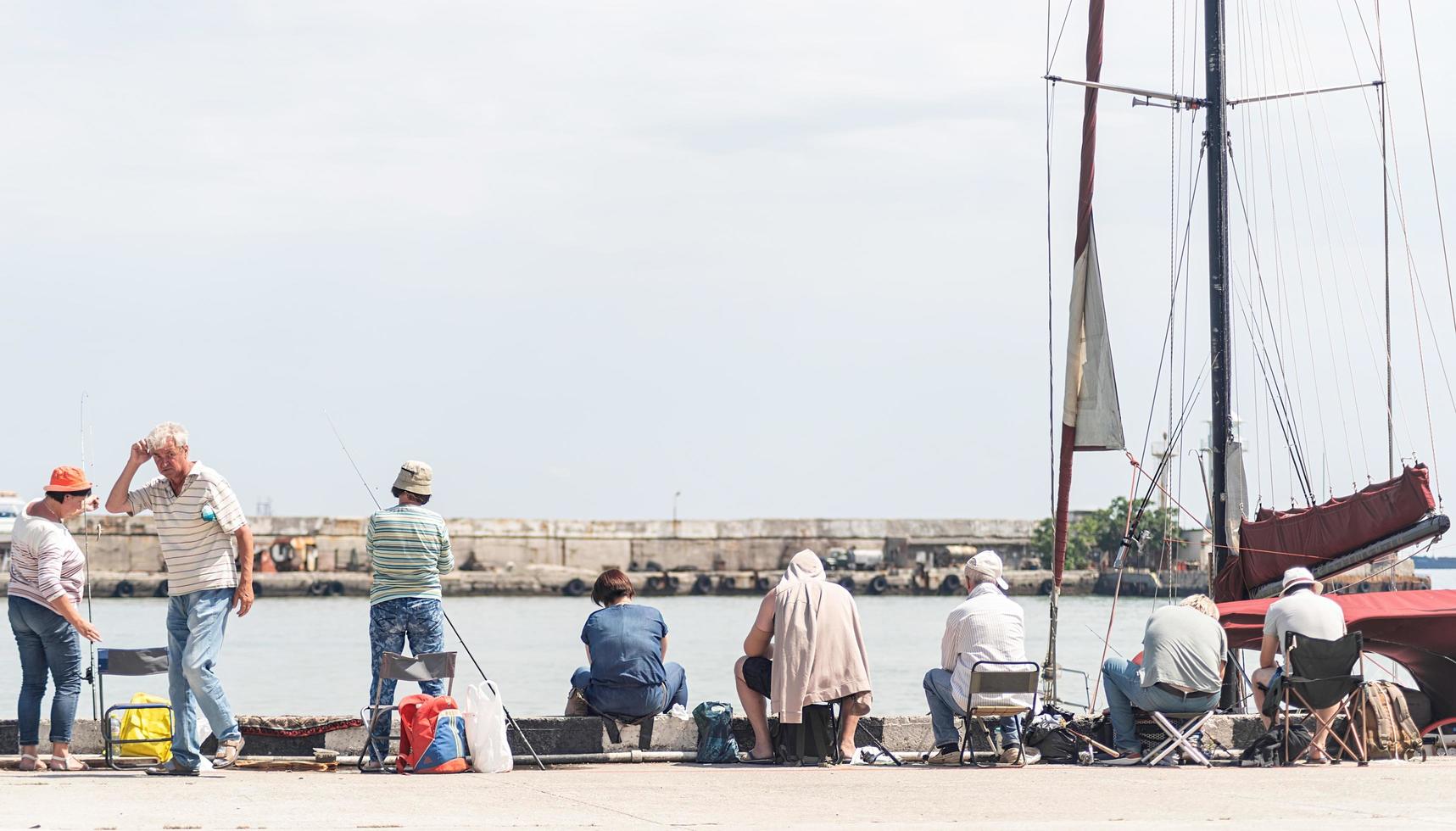 Yalta 2021- People fishing on the embankment, boats and yachts on the background photo