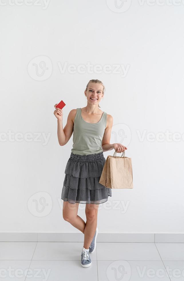 Mujer sonriente sosteniendo bolsas de compras ecológicas y tarjeta de crédito foto