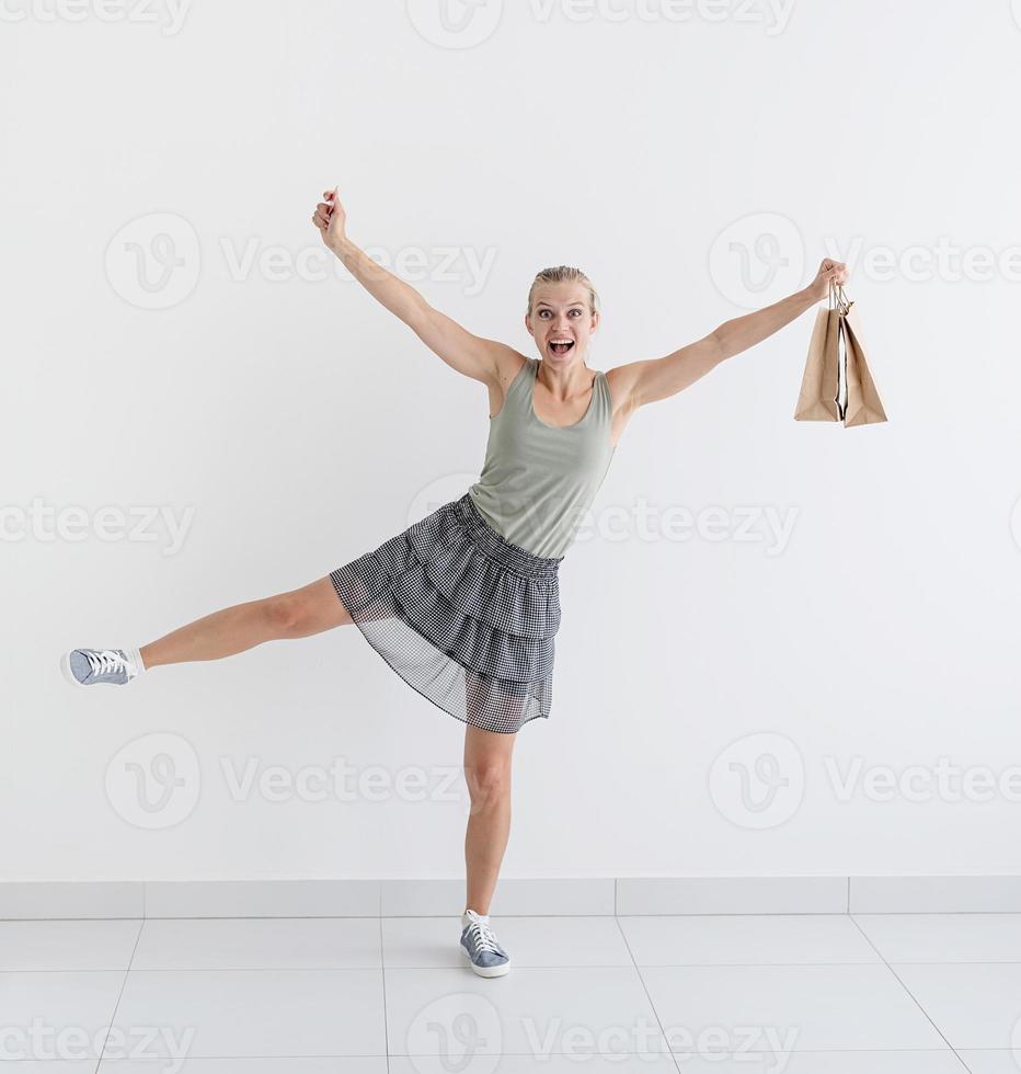 Mujer sonriente bailando con bolsas de compras ecológicas y tarjeta de crédito foto