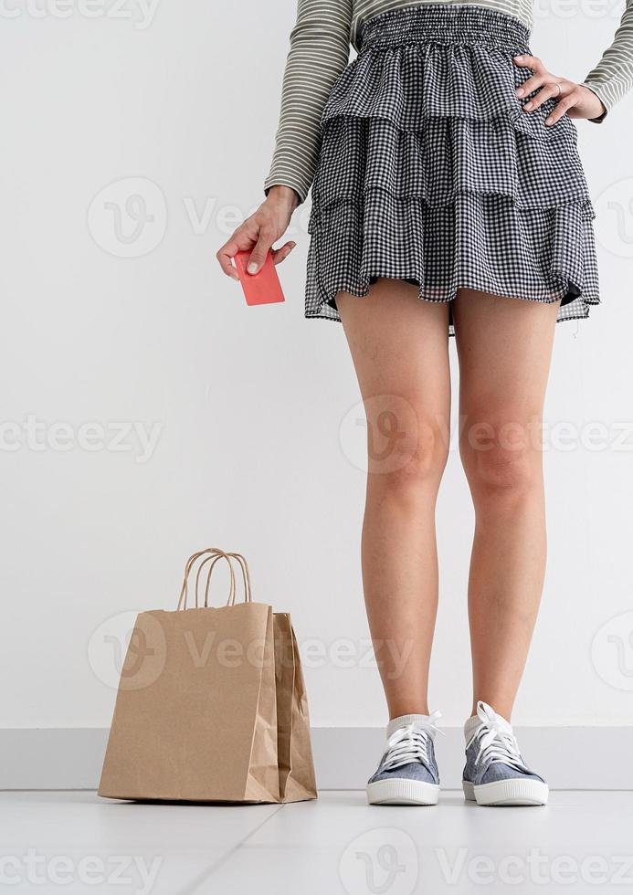 Woman holding credit card, eco friendly paper shopping bags nearby photo