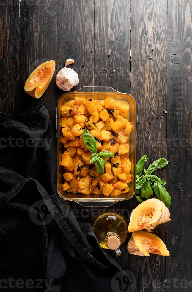 Freshly baked and juicy slices of pumpkin with ingredients on dark background photo