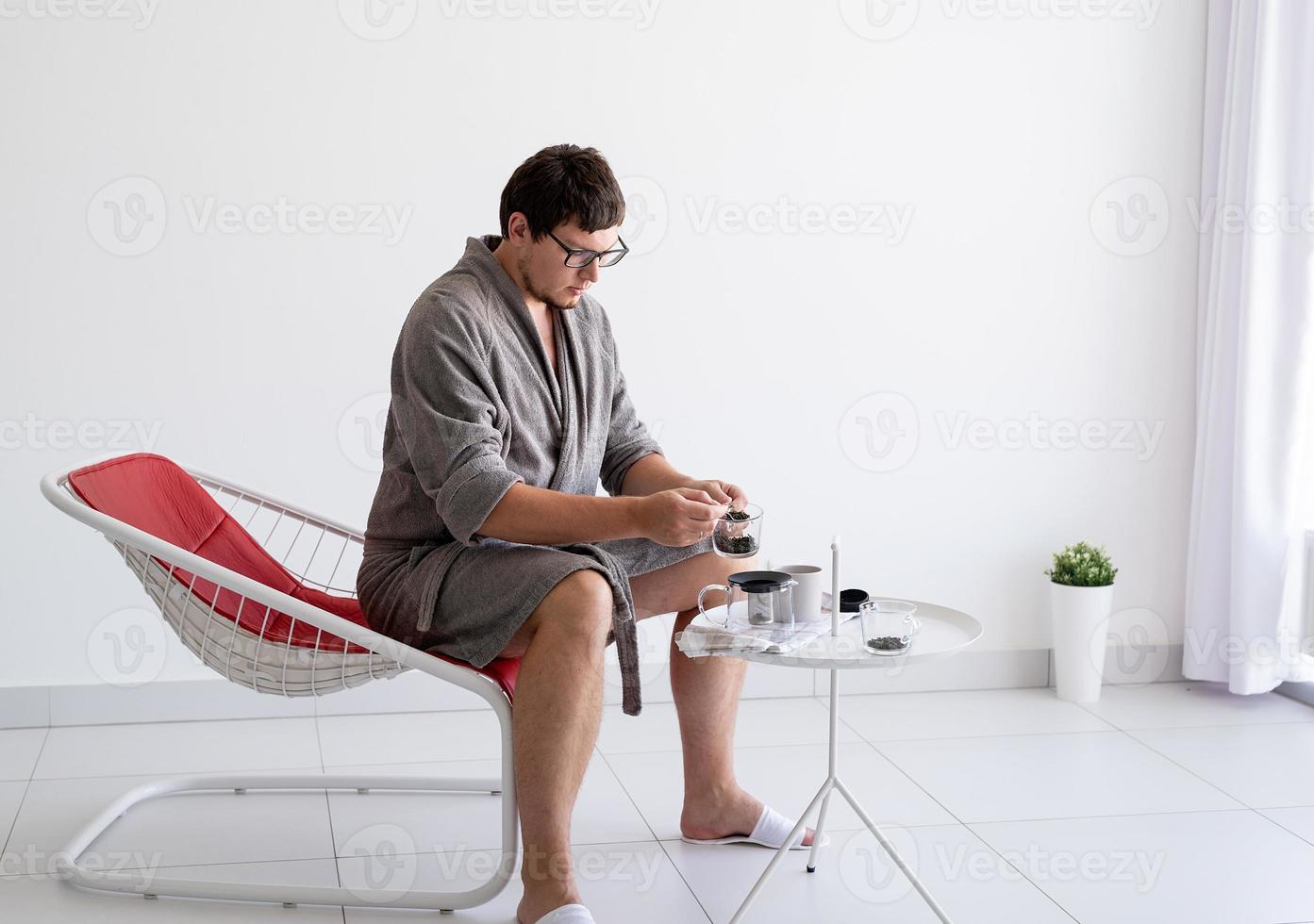 Man sitting in bathrobe making tea at home photo