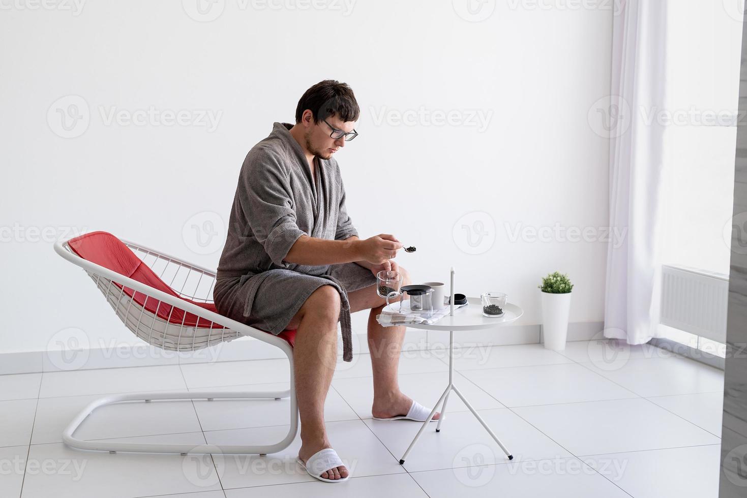 Man sitting in bathrobe making tea at home photo