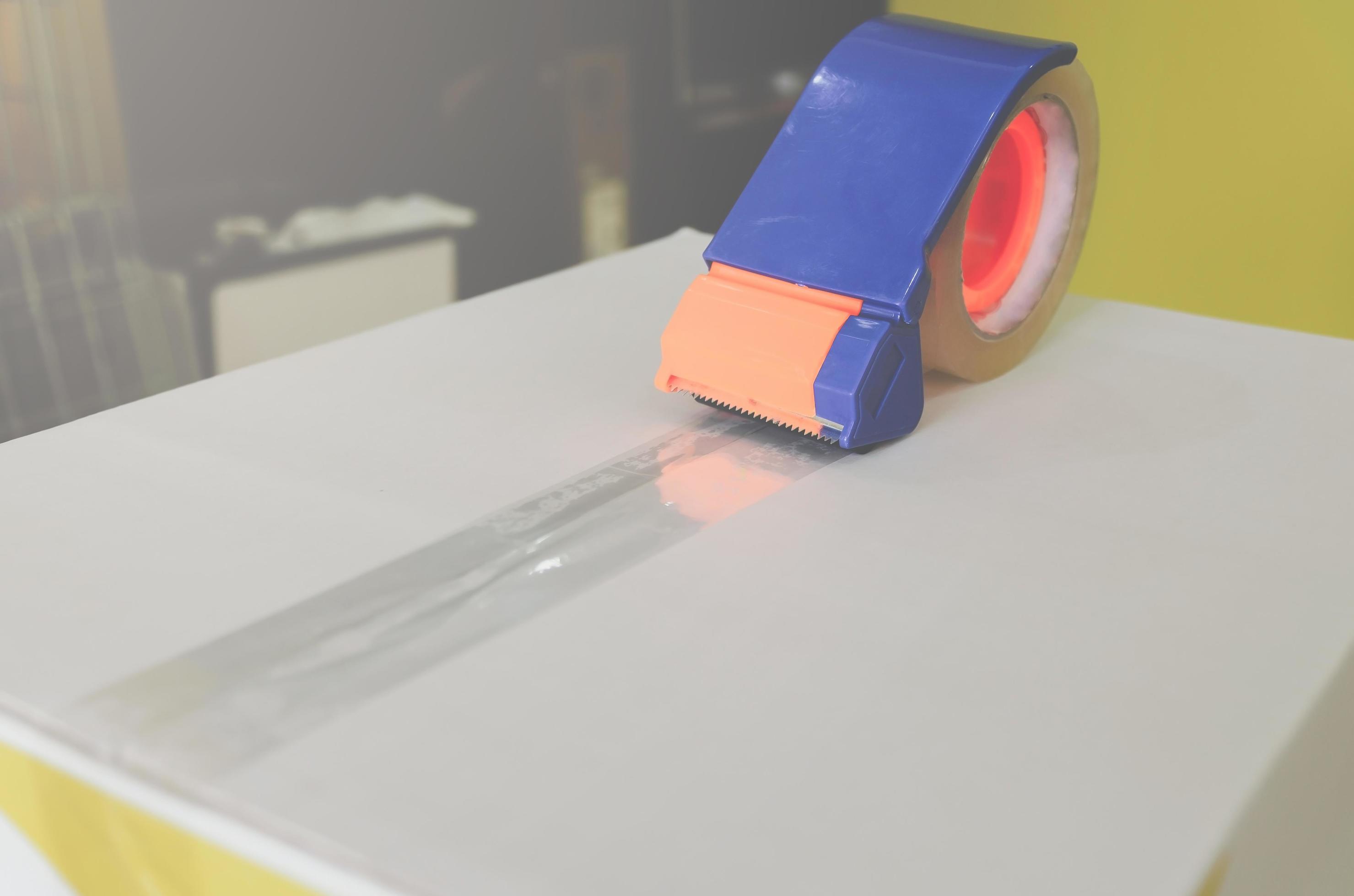 Preparing parcel for shipping with scissors and scotch tape cutter