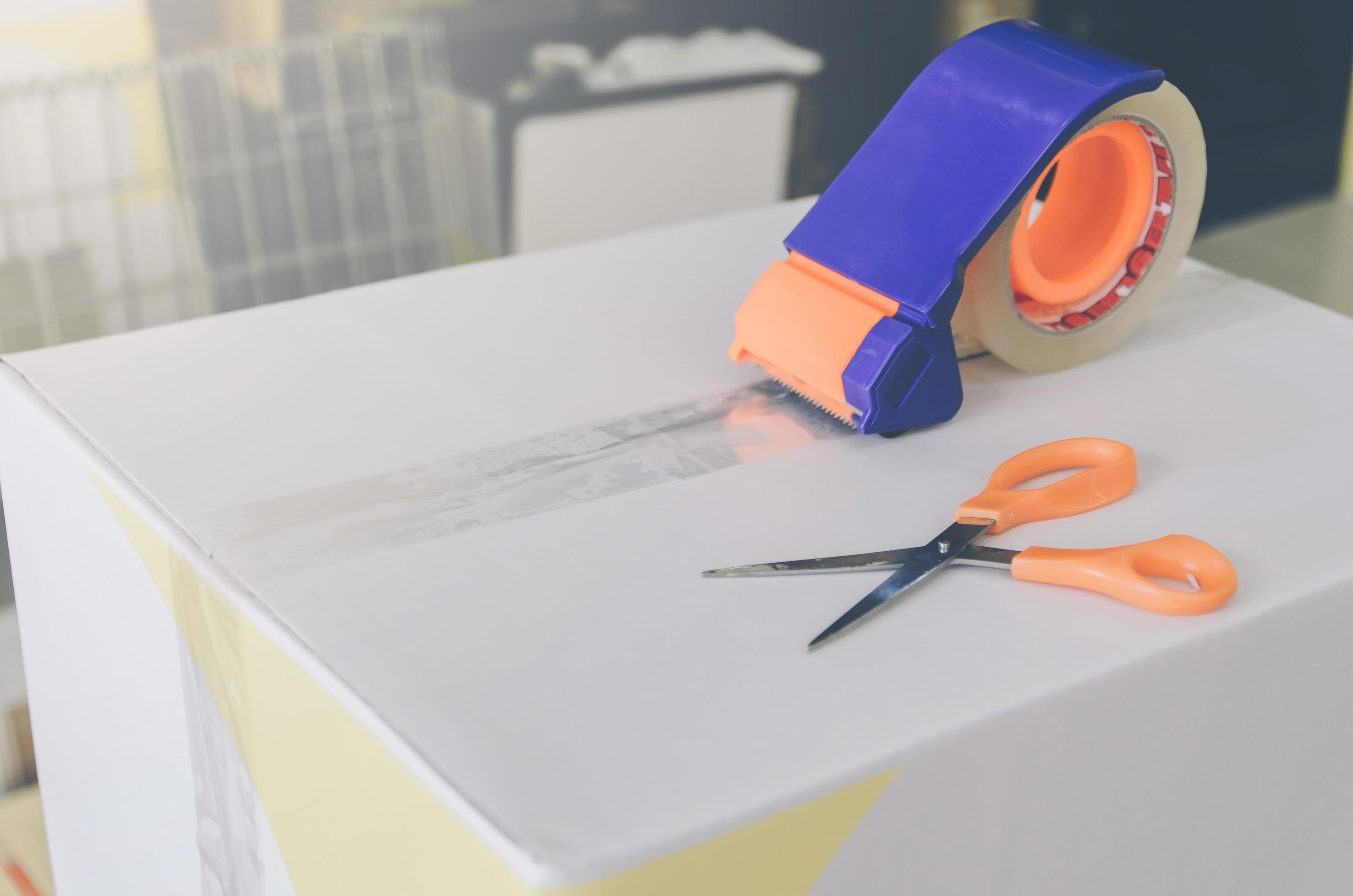 Preparing parcel for shipping with scissors and scotch tape cutter