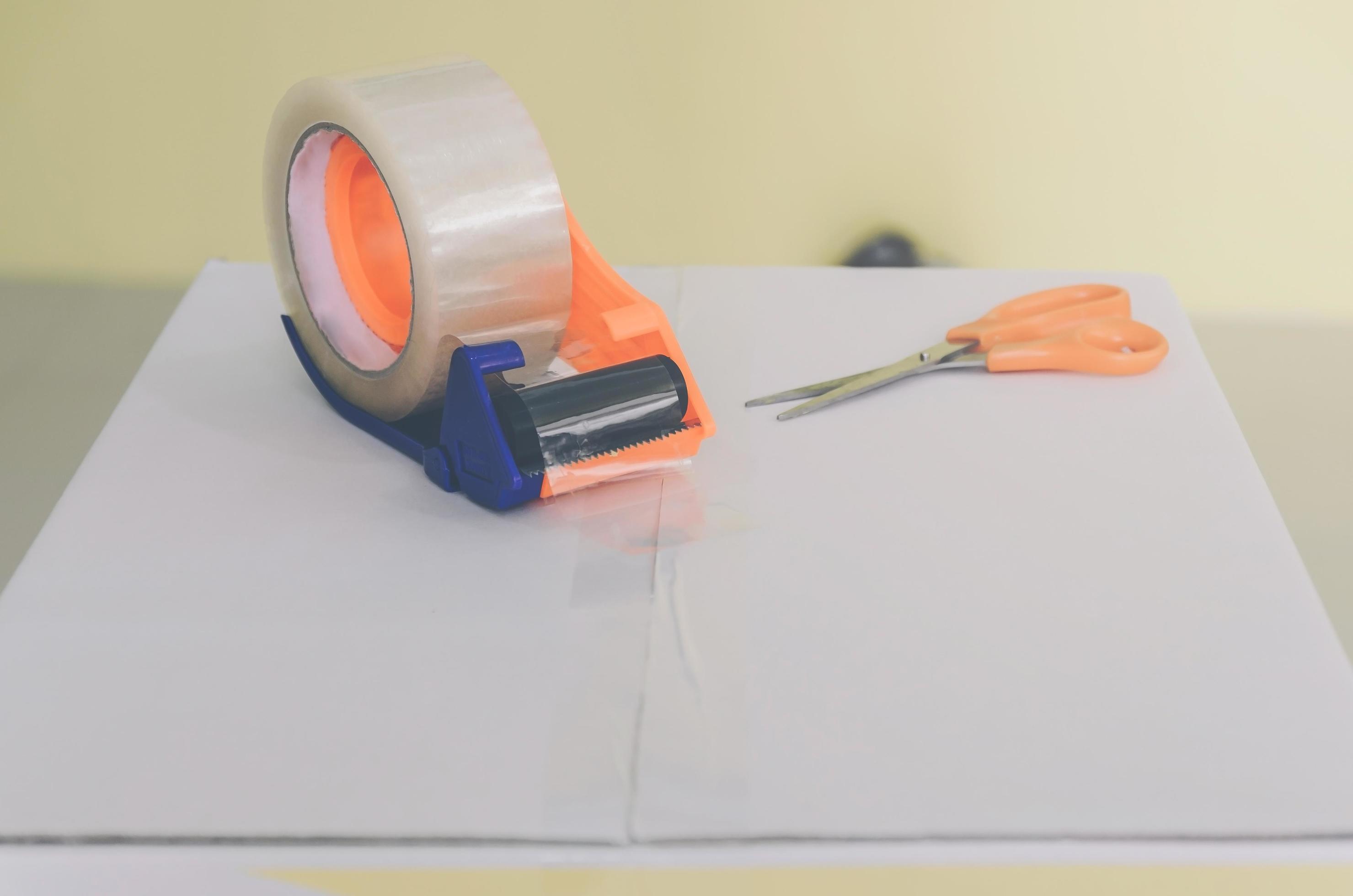 Preparing parcel for shipping with scissors and scotch tape cutter