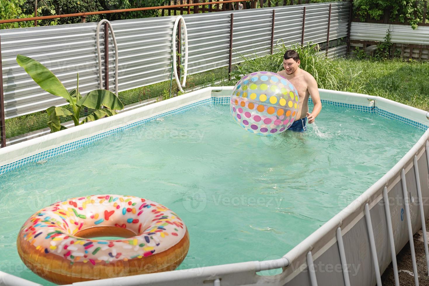 hombre divirtiéndose en la piscina, jugando con pelota inflable foto