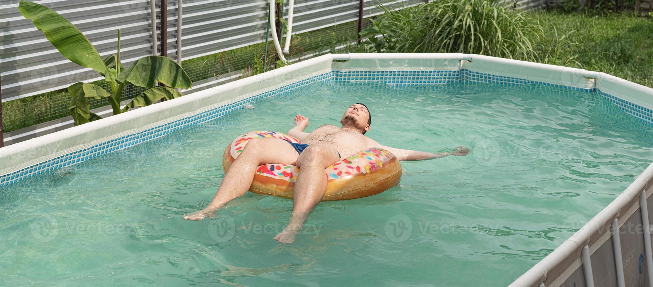 Joven tomando el sol en el tubo de natación inflable en la piscina foto