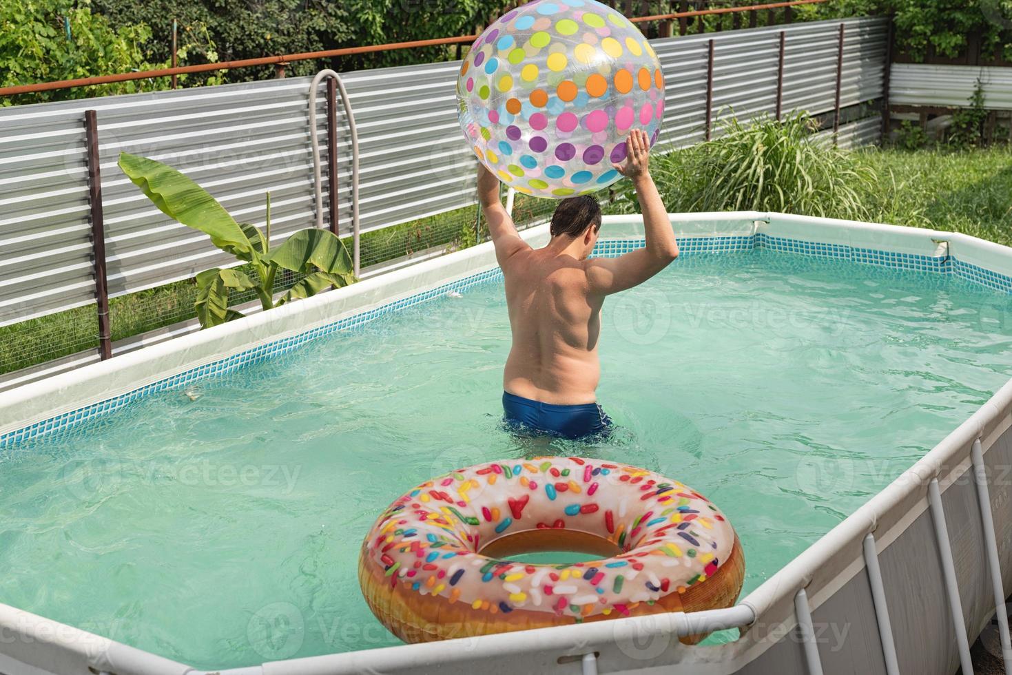 hombre divirtiéndose en la piscina, jugando con pelota inflable foto