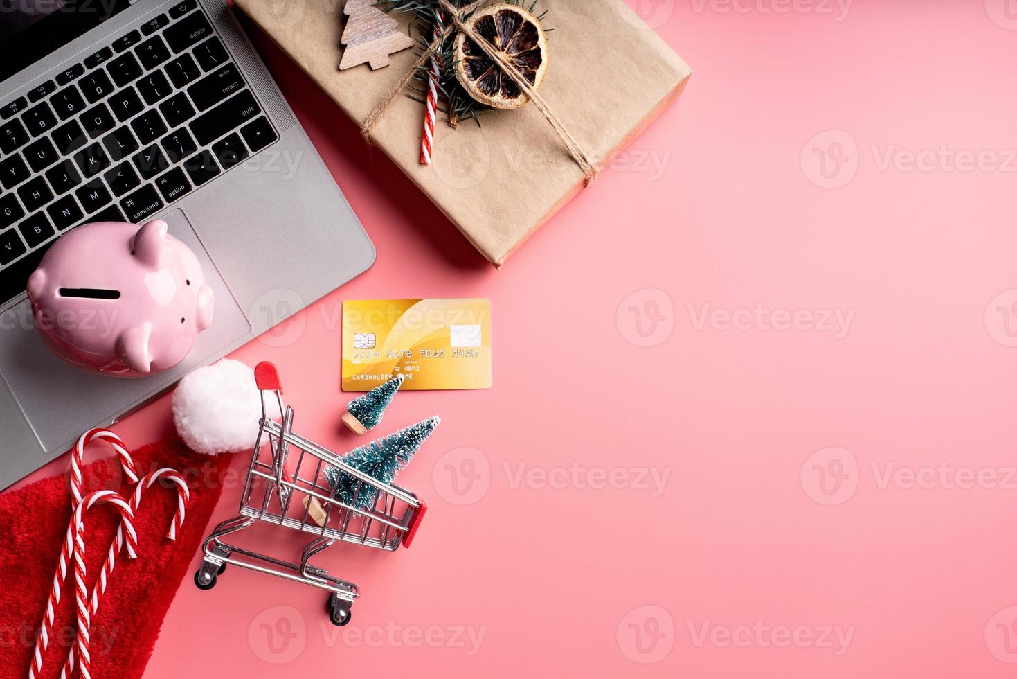 Christmas decorations and piggy bank on pink background photo