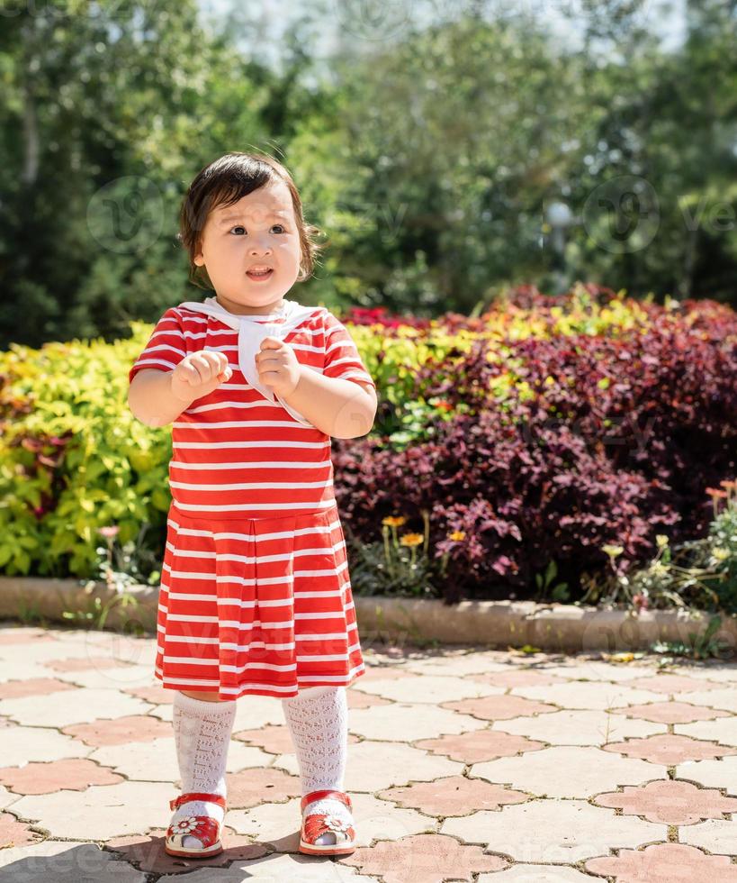 Adorable Asian infant girl dancing in the park photo