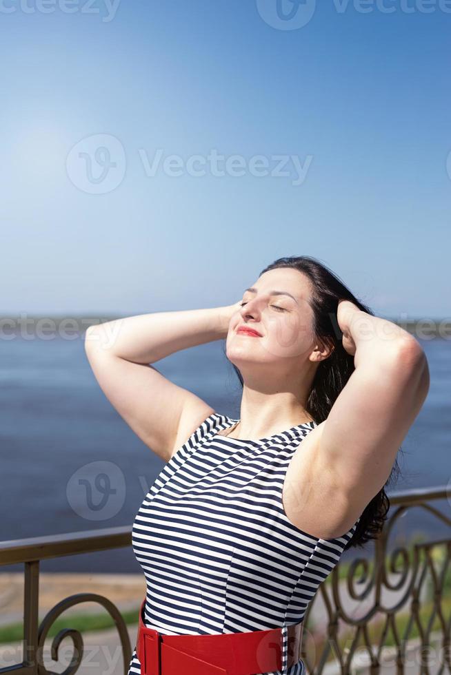 hermosa joven disfrutando del sol de pie junto al río foto