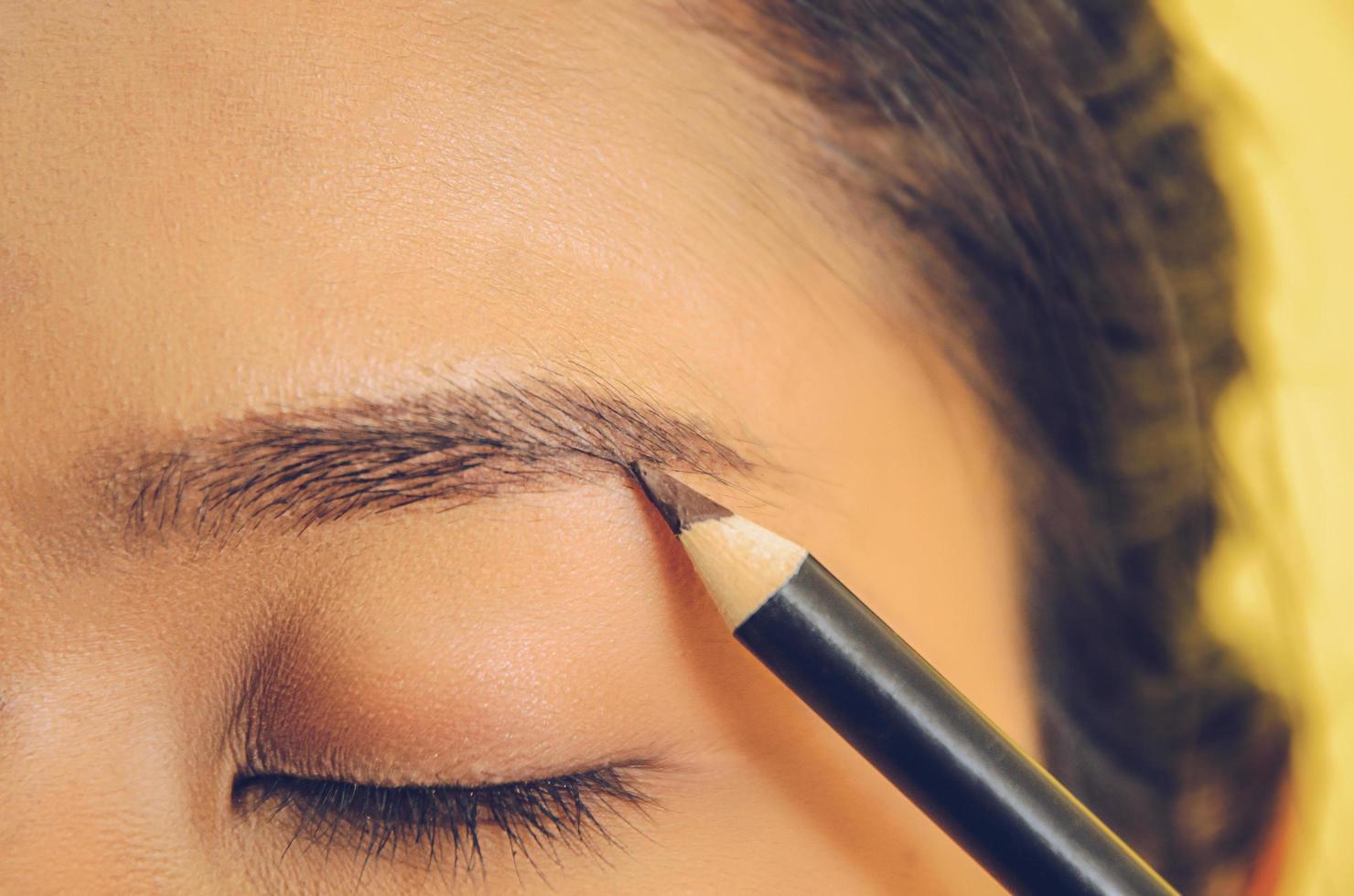 rostro de belleza de mujer asiática aplicando lápiz de cejas sobre la piel. foto