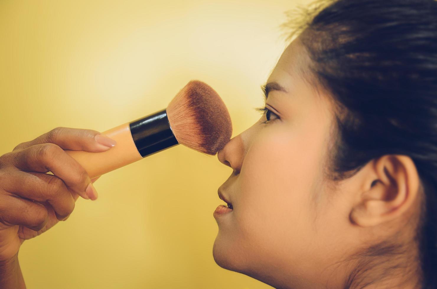 rostro de belleza de mujer asiática mediante la aplicación de pinceles en la piel con cosméticos. foto