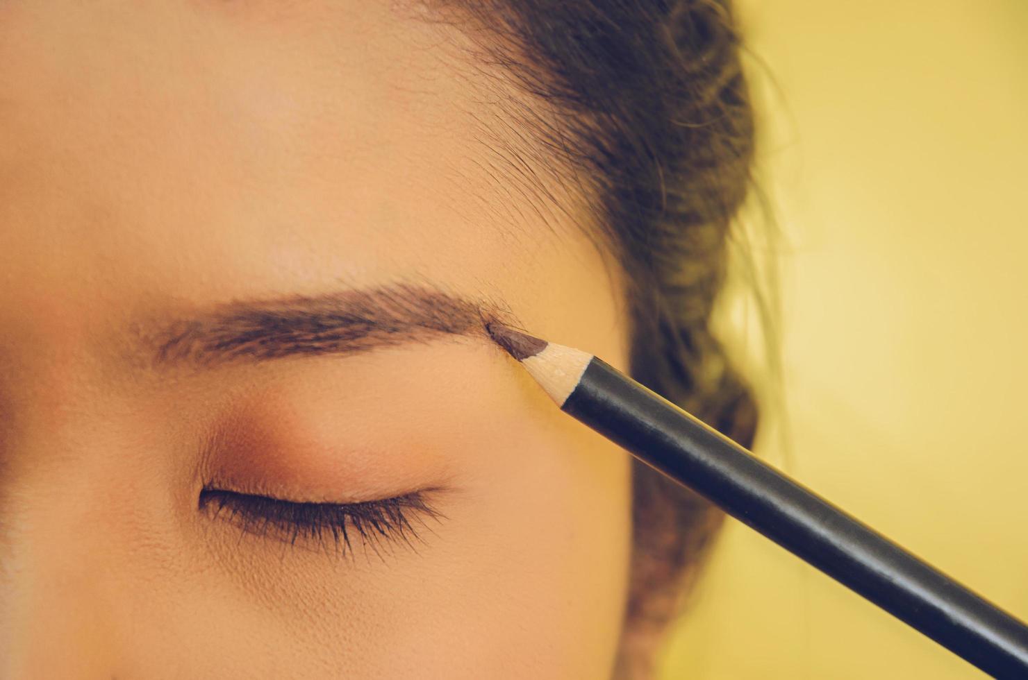 rostro de belleza de mujer asiática aplicando lápiz de cejas sobre la piel. foto