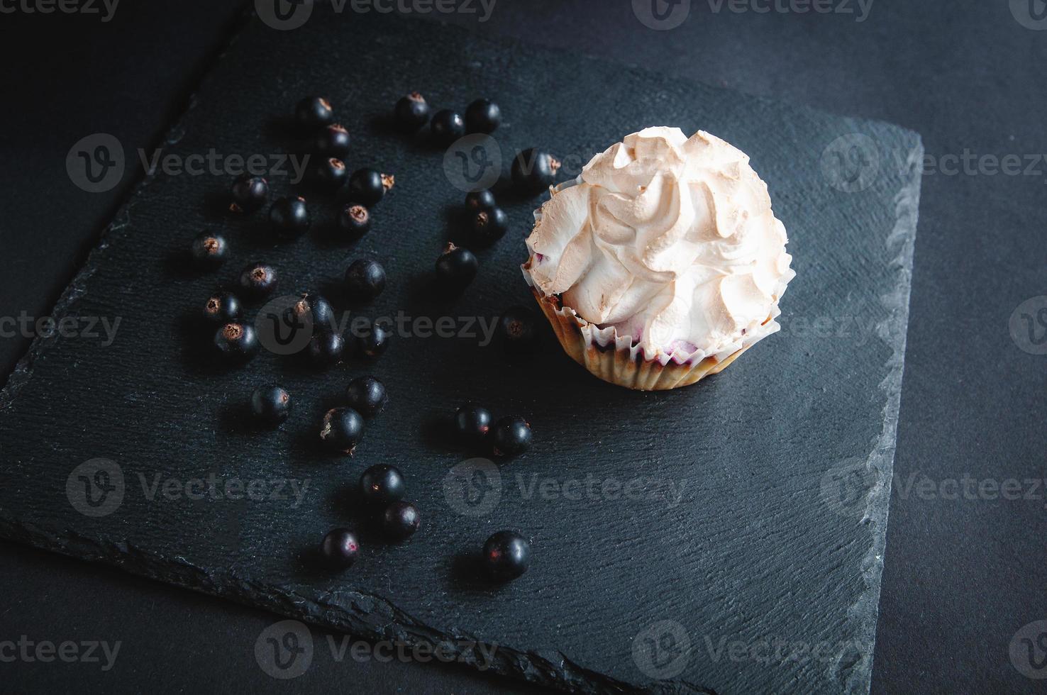 Muffin on a black background with currant berries. photo