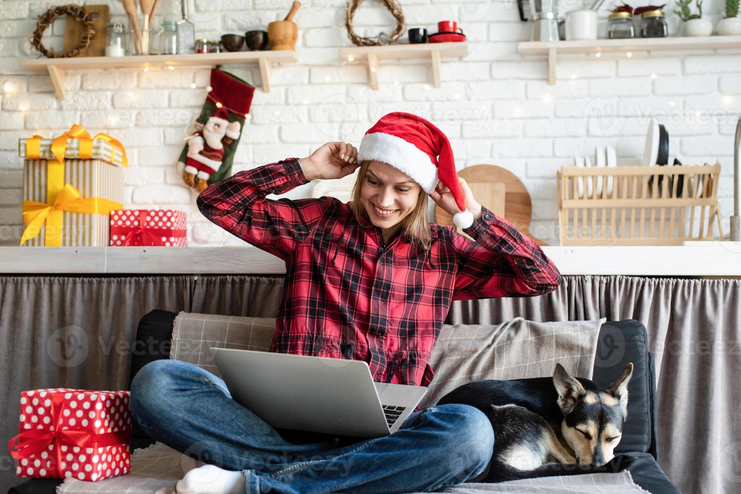 Woman in santa hat greeting her friends in video chat on laptop photo