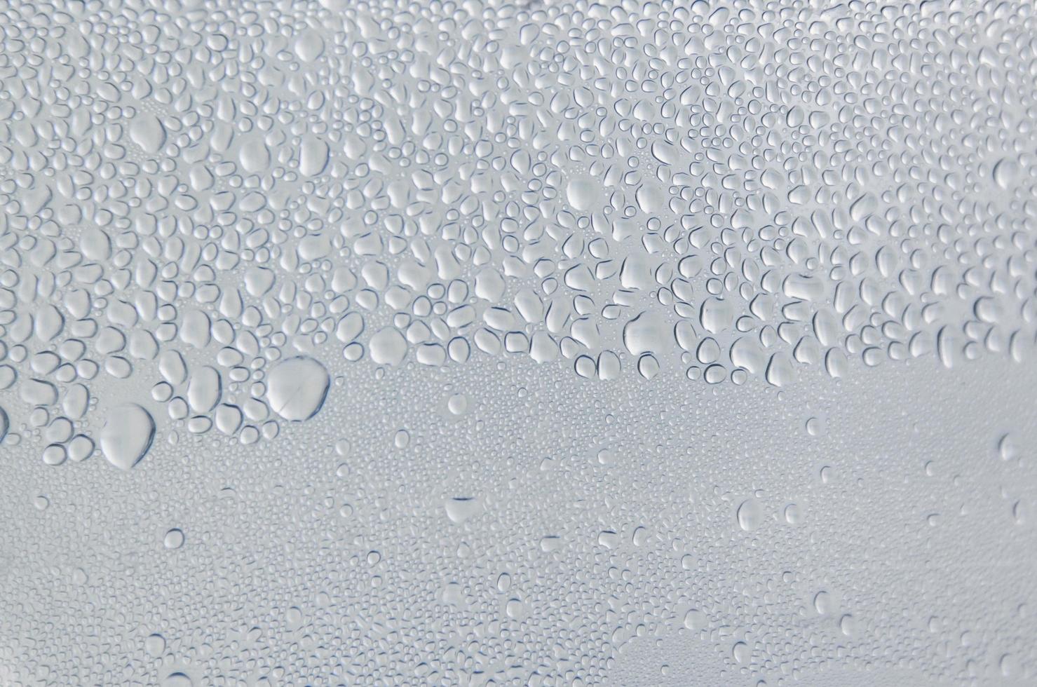 Fondo y papel tapiz por gota de lluvia y gotas de agua en la ventana. foto