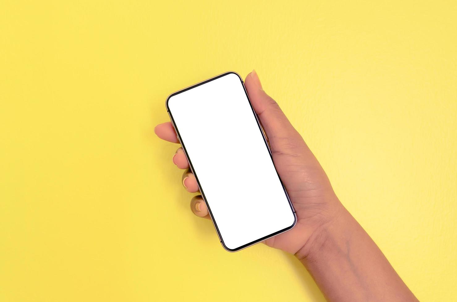 una mano que sostiene el teléfono inteligente con fondo de pantalla en blanco. foto