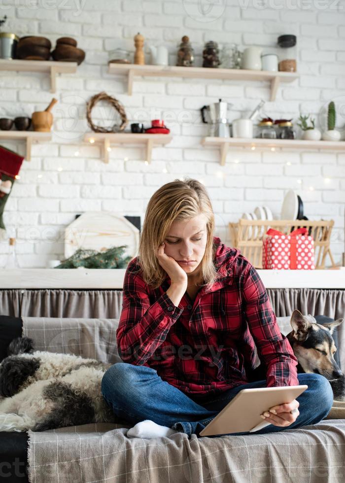 Young sad woman in working on tablet sitting on the couch photo