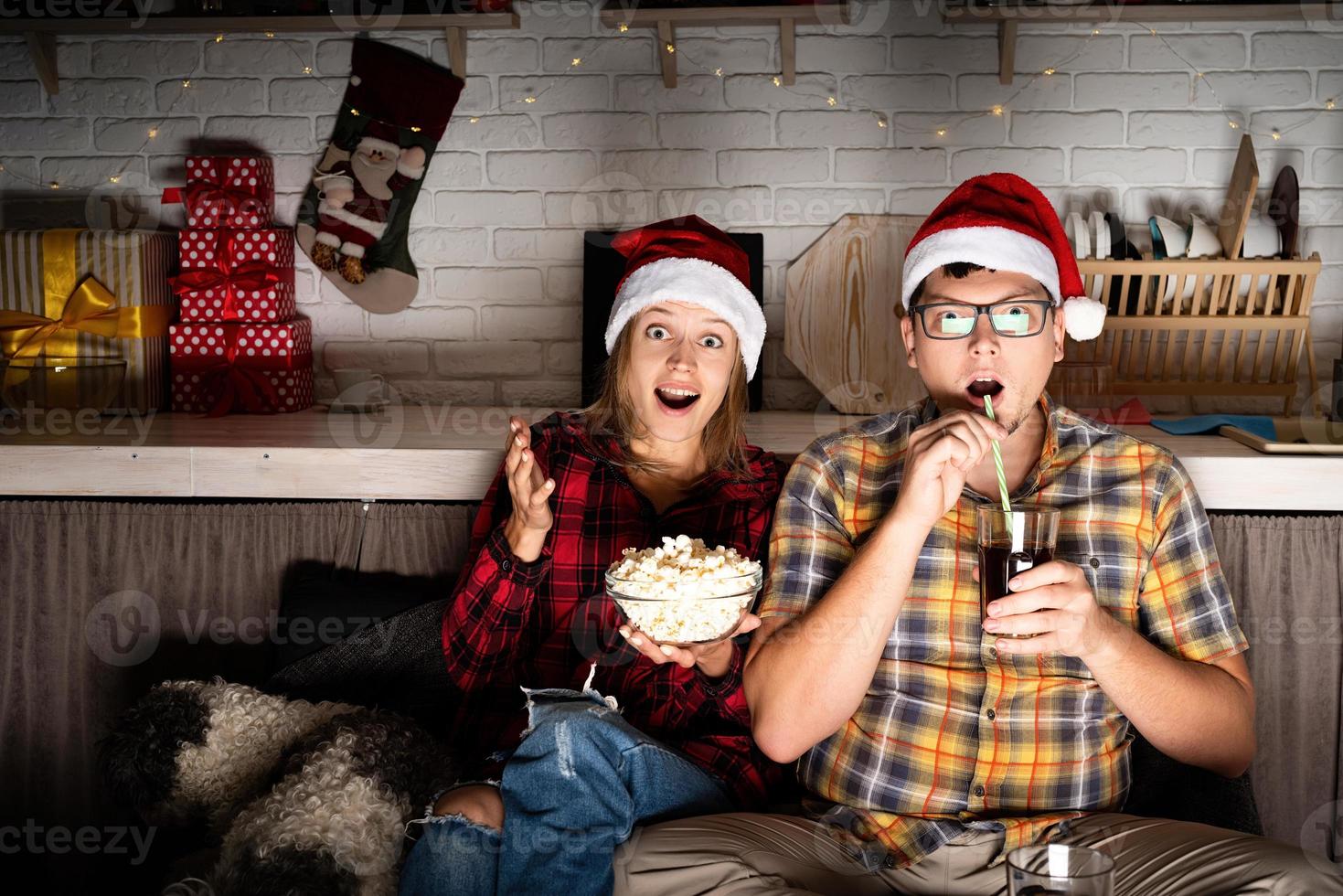 pareja viendo películas en casa en navidad apuntando a la pantalla foto