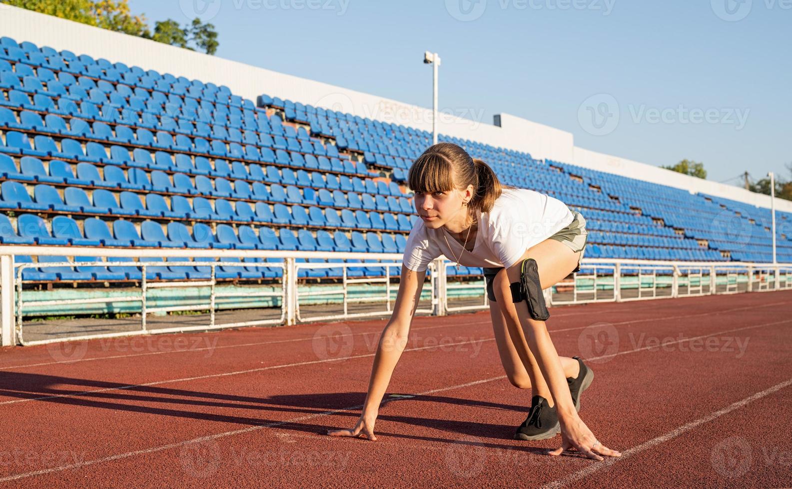 Woman on starting position, getting ready to run at stadium track photo