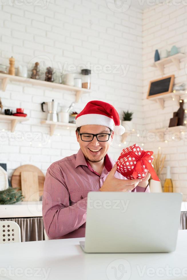 Hombre con gorro de Papá Noel saludando a sus amigos en el chat de video o llamar a la computadora portátil foto