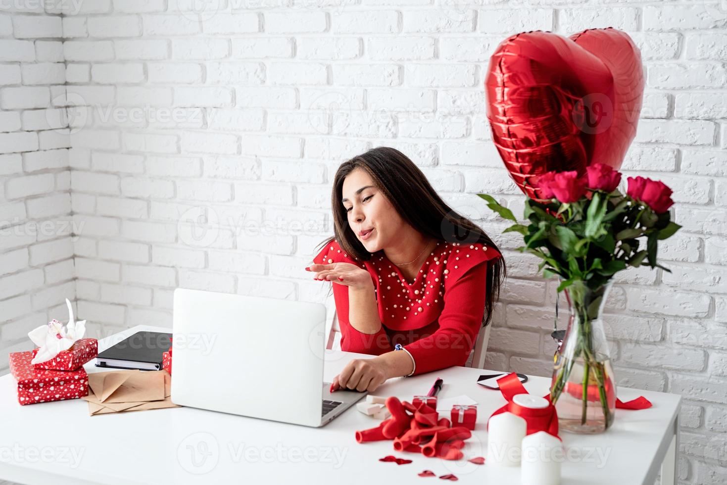 Woman dating online blowing a kiss over white brick wall background photo