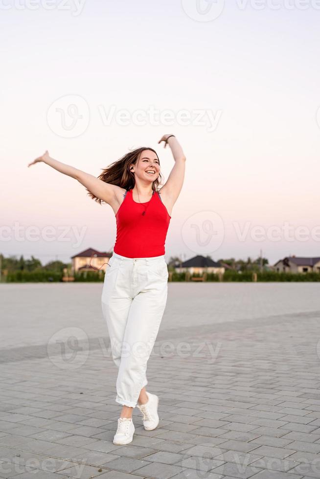 Teenage girl listening to the music dancing in the park photo