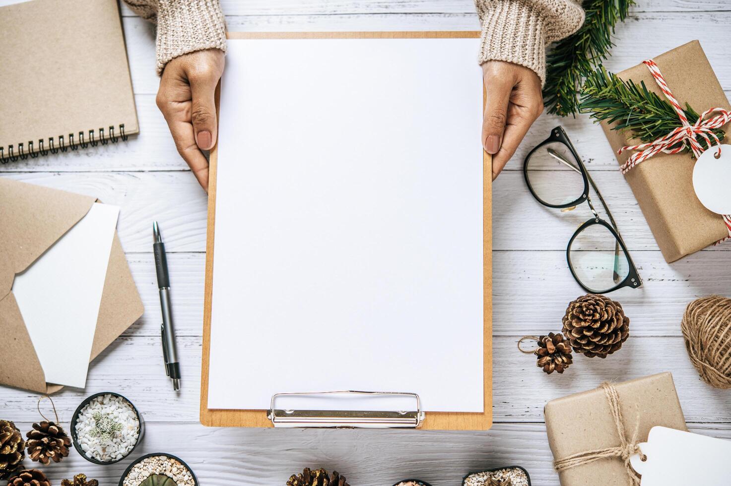 Hand holds clipboard on a white wooden table photo