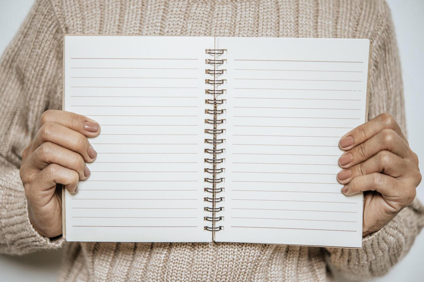 A woman who wears a long sleeve holds a notebook open photo