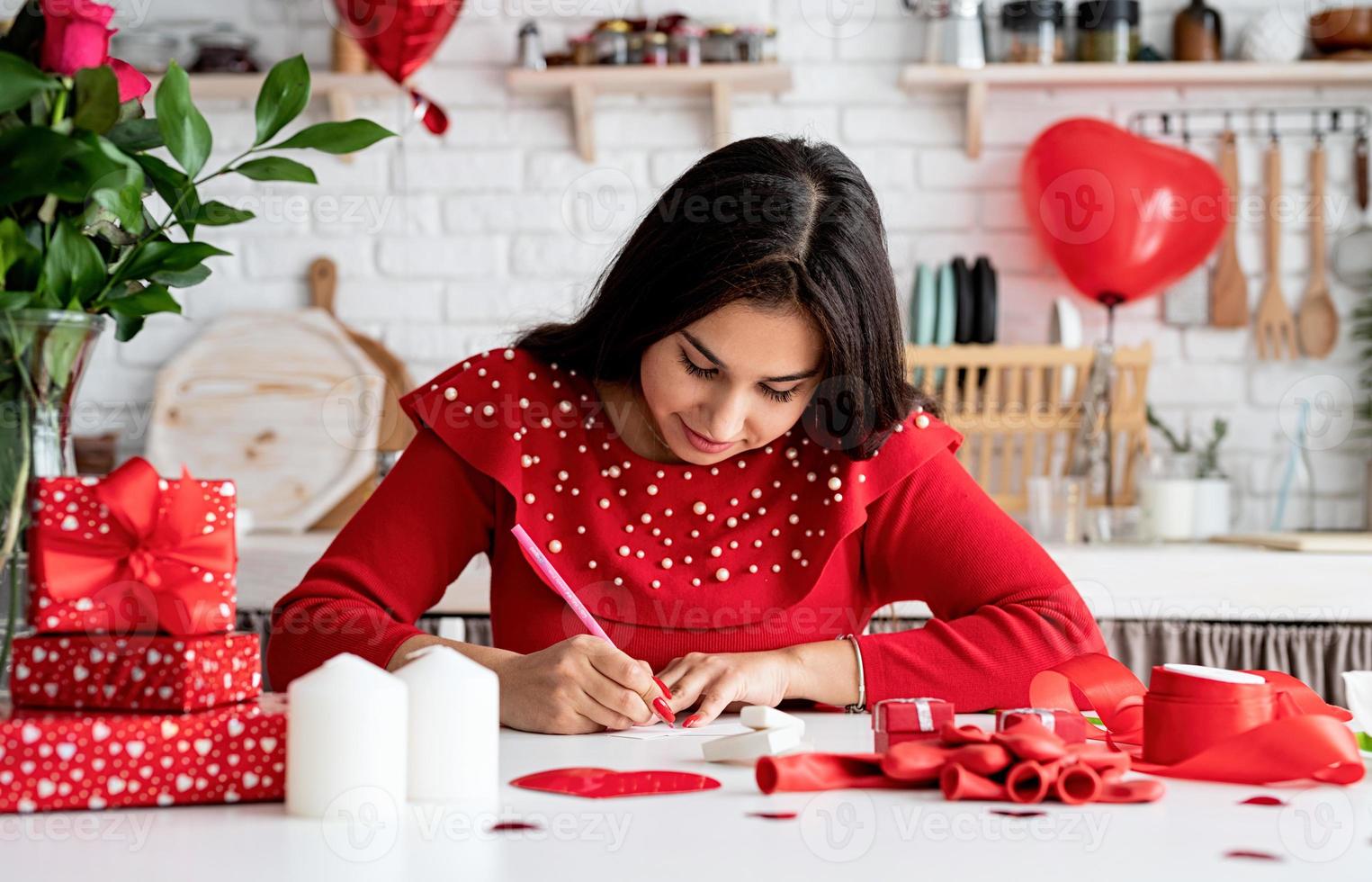 Woman  writing love letter sitting at the decorated kitchen photo