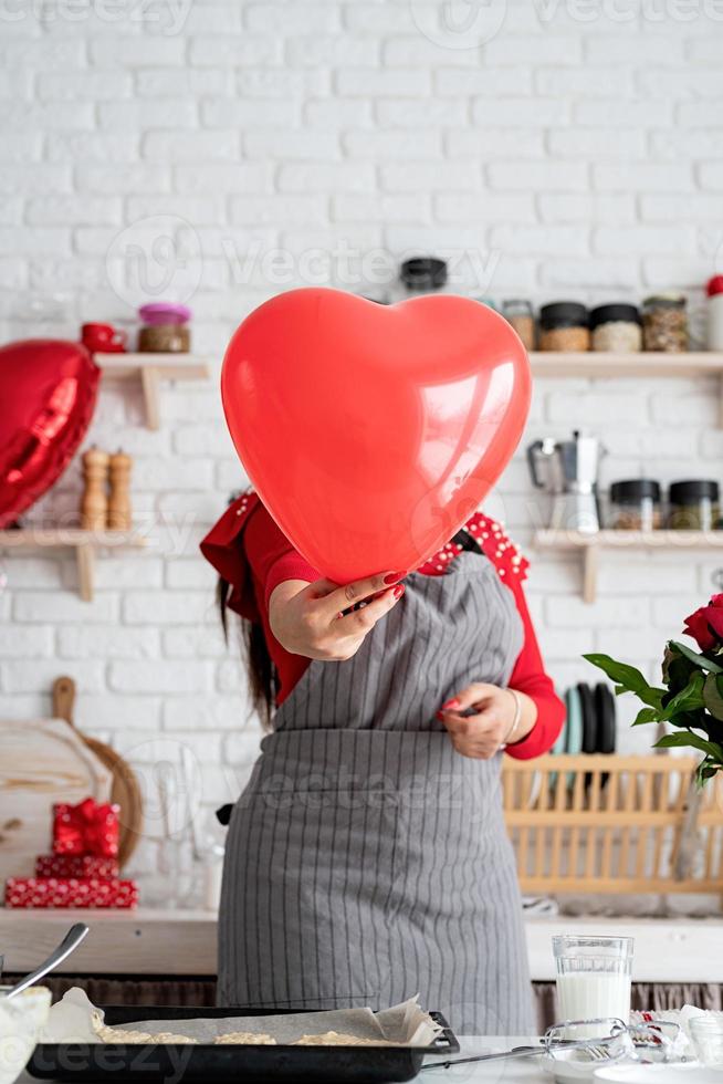 mujer en vestido rojo y delantal gris con globo de corazón rojo foto