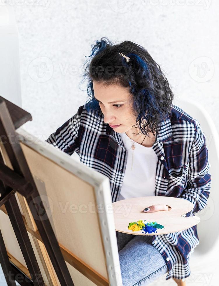 Creative woman with blue dyed hair painting in her studio photo