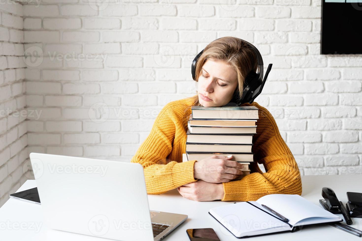 Young woman in black headphones sleeping on a stack of books photo